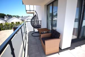a balcony with a chair and a wooden table at Apartamenty Morze Plażowa 4A i 4B in Sarbinowo