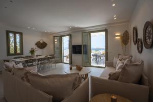 Paros Breeze Luxury Villa في دريوس: غرفة معيشة مع كنب وطاولة وغرفة طعام