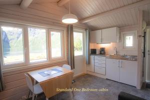 a kitchen with a table and two windows in a room at Geirangerfjorden Feriesenter in Geiranger +17 photos