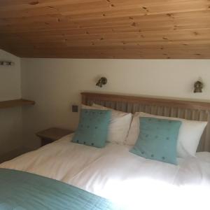 a bedroom with a white bed with blue pillows at Chestnut,1 bedroom loft apartment with wood burner in Cardigan