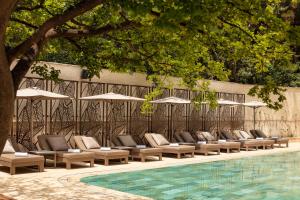 a row of lounge chairs and umbrellas next to a pool at Sheraton Grand Tbilisi Metechi Palace in Tbilisi City