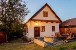 una pequeña casa blanca con una mesa delante en Jotaferien Transylvanian Cottage with Fireplace, 