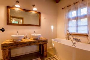 bagno con 2 lavandini, vasca e specchio di Jotaferien Transylvanian Cottage with Fireplace 