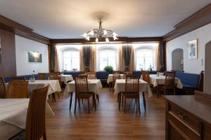 ein Esszimmer mit Tischen, Stühlen und Fenstern in der Unterkunft Hotel Pension Kandolf in Tamsweg