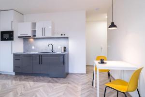 eine Küche mit einem Waschbecken, einem Tisch und gelben Stühlen in der Unterkunft Brno Center View Apartement A - with self check-in in Brünn
