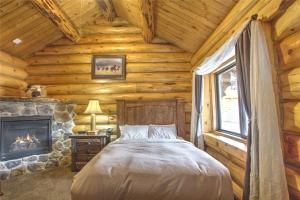 ein Schlafzimmer mit einem Bett und einem Kamin in einer Blockhütte in der Unterkunft Hibernation Station in West Yellowstone