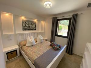 sypialnia z łóżkiem z poduszkami i oknem w obiekcie Villa Campana - Sartène w mieście Sartène