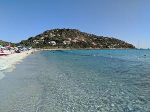 a beach with people in the water and an island at Casa Luna in Torre delle Stelle