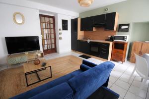 uma sala de estar com um sofá azul e uma cozinha em Le petit Monlogis - Calme - Wi-Fi em Angoulême