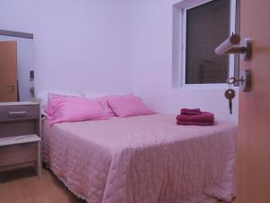 Schlafzimmer mit einem Bett mit rosa Bettwäsche und einem Fenster in der Unterkunft Casa de Nômades Digitais in Mindelo