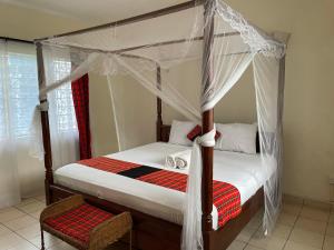 ein Schlafzimmer mit einem Himmelbett und einem Stuhl in der Unterkunft Maasai Resort in Mombasa