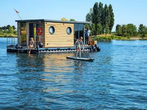 a woman on a paddle board in the water with a house at Nice houseboat in Kinrooi for rent in Kinrooi