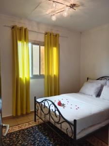 a bedroom with a bed with yellow curtains and a window at Résidence Hôtelière l'Océane in Kribi