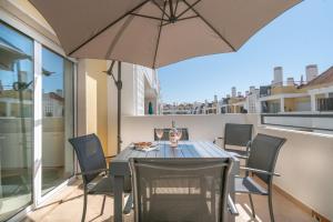 a table and chairs with an umbrella on a balcony at Delightful Cabanas 2 Bedroom apartment in Cabanas de Tavira
