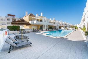 a resort with a swimming pool and benches and buildings at Delightful Cabanas 2 Bedroom apartment in Cabanas de Tavira