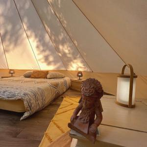- une chambre avec un lit et une statue dans une tente dans l'établissement Le Tipi Ethnique au bord de la rivière, à Mios