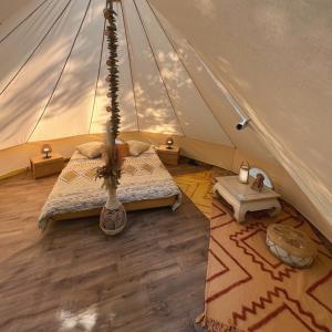 Le Tipi Ethnique au bord de la rivière في ميوس: غرفة نوم في خيمة مع سرير وسجادة