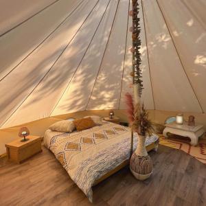 - une chambre avec un lit dans une tente dans l'établissement Le Tipi Ethnique au bord de la rivière, à Mios