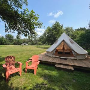 米奧的住宿－Le Tipi Ethnique au bord de la rivière，木甲板上的两把椅子和一顶帐篷