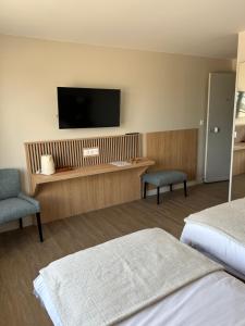 um quarto de hotel com duas camas e uma televisão de ecrã plano em LE RELAIS DES HAYONS 