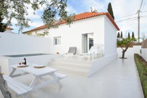 un patio blanco con mesa blanca y sillas en Casa do Povo (casa com piscina no centro de Alcácer) en Alcácer do Sal