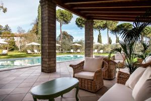 eine Terrasse mit Stühlen, einem Tisch und einem Pool in der Unterkunft Poggio delle Molare Adults-Only Retreat in Bracciano
