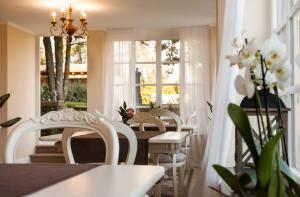 comedor con sillas blancas, mesa y ventanas en Poggio delle Molare Adults-Only Retreat, en Bracciano