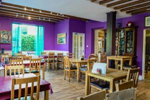 a restaurant with purple walls and wooden tables and chairs at Manorbier House - St Anne's Room in Tenby