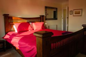 a bedroom with a large wooden bed with red sheets at Manorbier House - St Anne's Room in Tenby