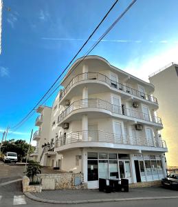 Un grand bâtiment blanc avec balcon se trouve dans une rue. dans l'établissement White Pearl Apartments, à Bar