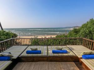 a bench on a deck with a view of the beach at SaffronStays Stella Maris - Luxury Beach Front Villa Near Redi Beach in Querim