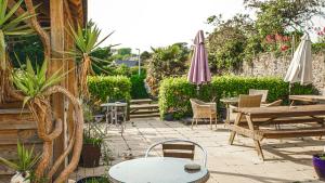 a patio with tables and chairs and umbrellas at Manorbier House - St Anne's Room in Tenby