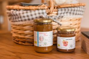 two jars of honey on a table with a basket at LA TORRE DEL MANGHEN: Agri-alloggio indipendente in Rota d'Imagna