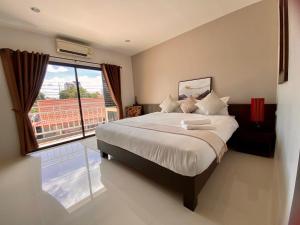 - une chambre avec un grand lit et une grande fenêtre dans l'établissement SD Residence I Naiyang Beach I HKT Airport, à Ban Bo Han