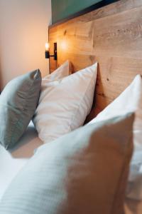 1 cama con almohadas blancas y cabecero de madera en Pur-INN das Gästehaus, en Purbach am Neusiedlersee