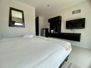 1 dormitorio con 1 cama blanca grande y espejo en SD Residence I Naiyang Beach I HKT Airport, en Ban Bo Han