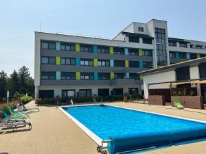 a swimming pool in front of a large building at Lila Apartman in Balatonföldvár