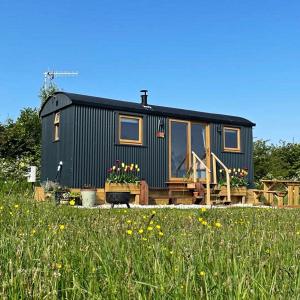 a green tiny house sitting on top of a field at Luxury Shepherd Hut in the Peak District in Bakewell