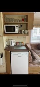 a small kitchen with a microwave and a refrigerator at S452 Golden Palm Resort in Chapel Saint Leonards