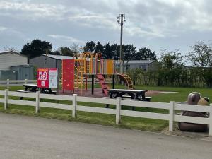 a park with a playground with a white fence at S452 Golden Palm Resort in Chapel Saint Leonards
