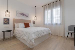 a white bedroom with a bed and a window at La Morada Cordobesa in Córdoba