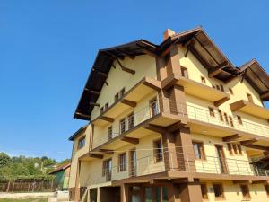 a tall yellow building with balconies on it at Agropensiunea Maya-Andrei in Bumbesti Pitic