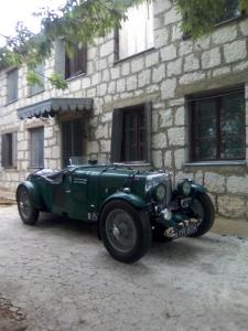 an old green car parked in front of a building at Leppo Guest House in Gacko
