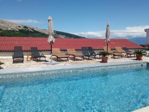 a swimming pool with chairs and umbrellas next to a building at KATY&MLADEN in Baška