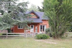 una pequeña casa de madera con una valla delante en Charmante maison en bois proche mer, en Saint-Jean-de-la-Rivière