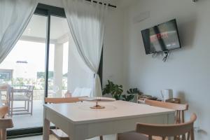 ein Wohnzimmer mit einem Tisch und einem TV an der Wand in der Unterkunft Dimore LE GRASTE - Made in Sicily in Noto