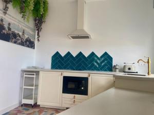 a kitchen with white cabinets and blue tiles on the wall at Precioso loft en Caión ROCHA, sobre la arena y el mar in Cayón