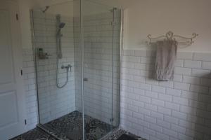 baño con ducha de cristal con azulejos blancos en Villa Léna, en Balatonederics