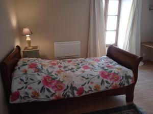 a bedroom with a bed with a floral bedspread at Charming detached 2 bedroom ancient house in medieval quarter of a small town in the Pays de la Loire, France in Sillé-le-Guillaume