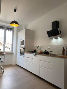 a white kitchen with white cabinets and a window at Le Condorcet. Charme et confort à Championnet in Grenoble